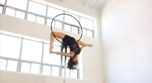 Eman suspended in a pose from an aerial hoop